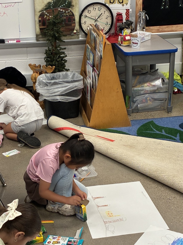 Children work on art projects on the floor. One child uses markers, while another uses building blocks.
