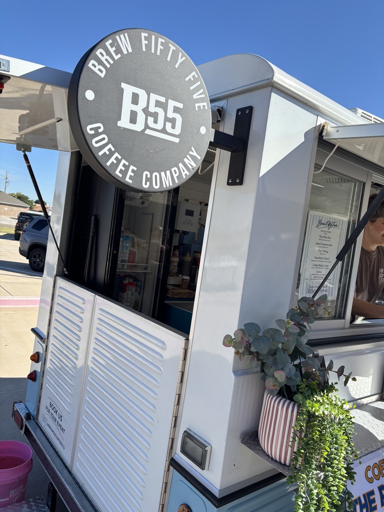 Brew Fifty Five coffee company truck with a sign and a potted plant. A man serves customers through a window.