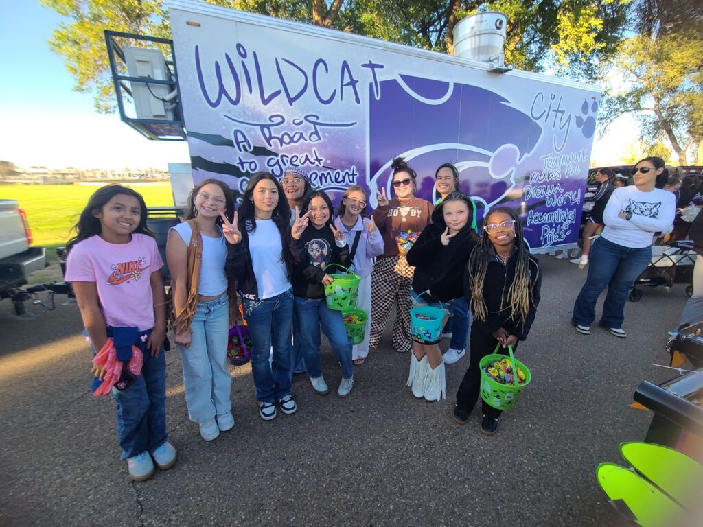 A group of young girls pose next to a decorated vehicle labeled "Wildcat" with "At Best" written below.