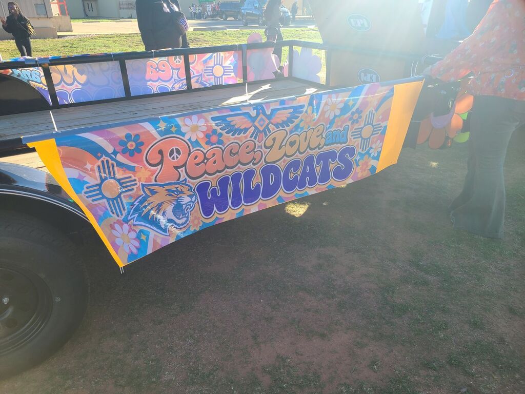 A colorful trailer with a banner reading "Peace, Love, Wildcats" in bold, multi-colored letters.