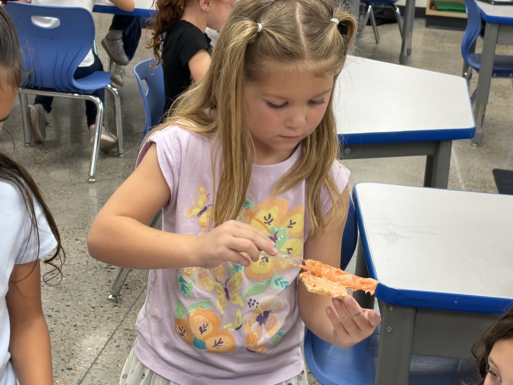 A girl holds a piece of pizza, with her hands, in front of her face.