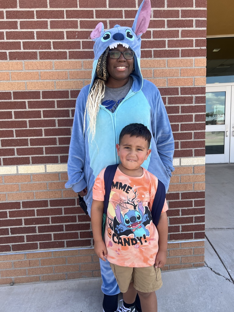 An adult staff member wearing a Stitch costumes. In front of her is a student with Disney Stitch shirt.