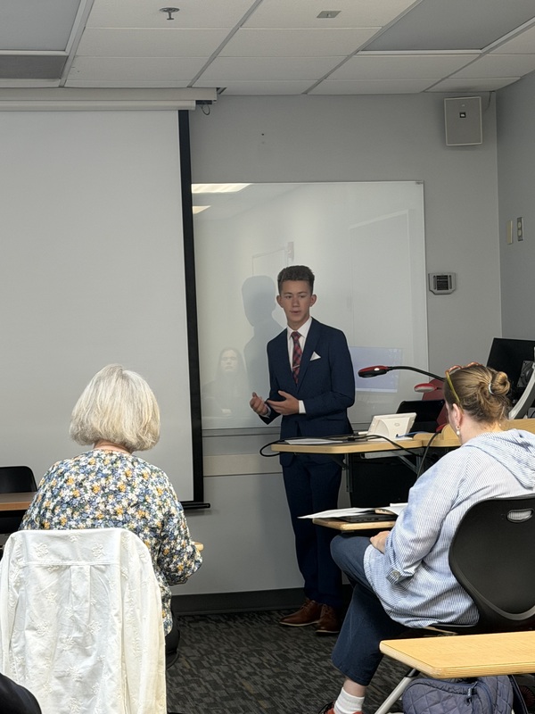 Grayson presenting in front of a room.