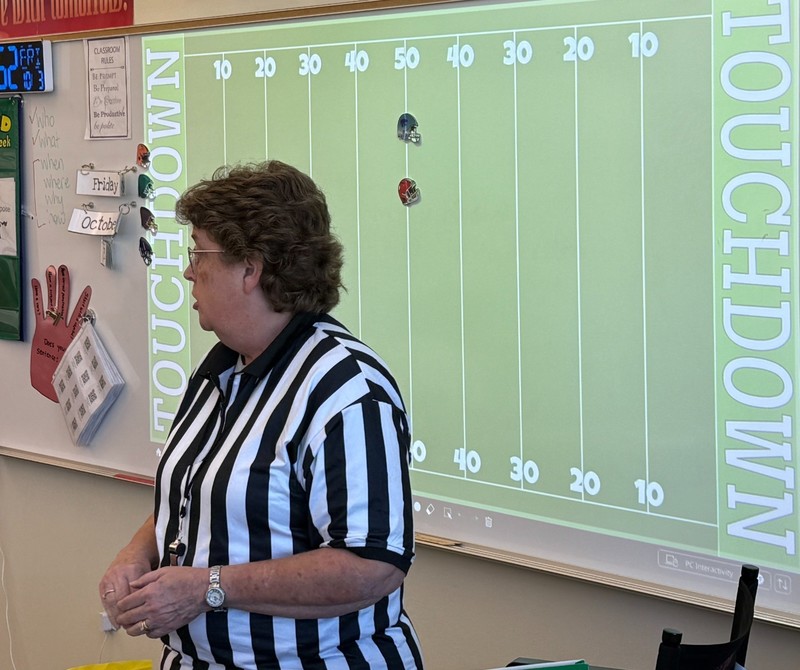 Gwyn Del Toro, dressed as a referee, asks her students review questions using a football themed game.