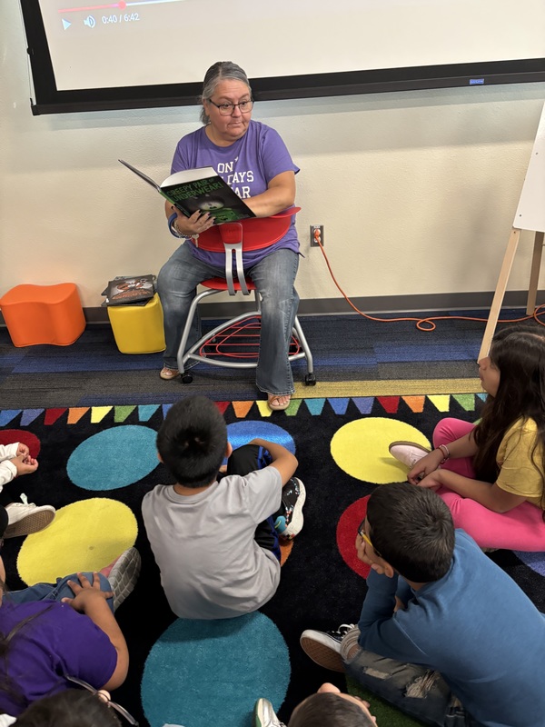Librarian reading to students. Students are watching intently.
