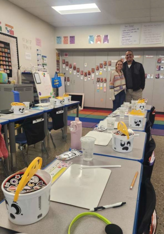 Teacher standing next to a man. They are behind desks with happy meals