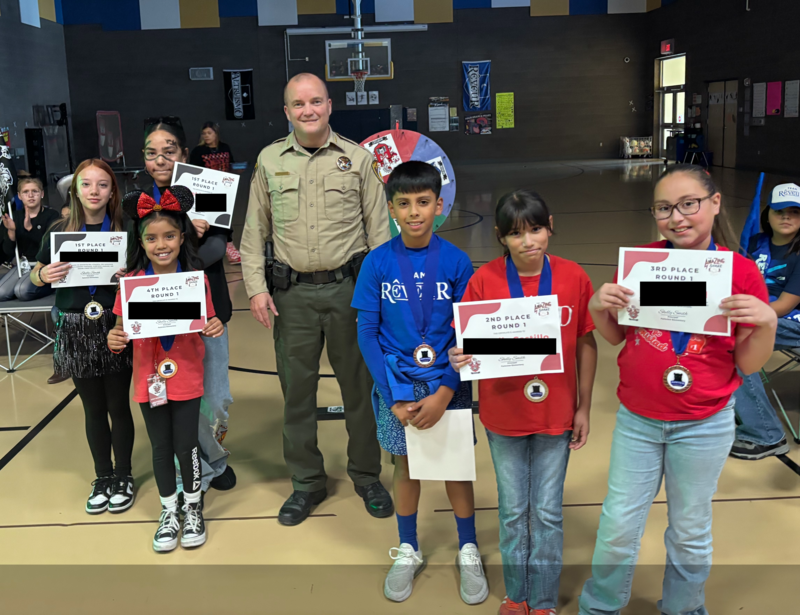 Six students holding up certificates. Man standing in the middle of them.