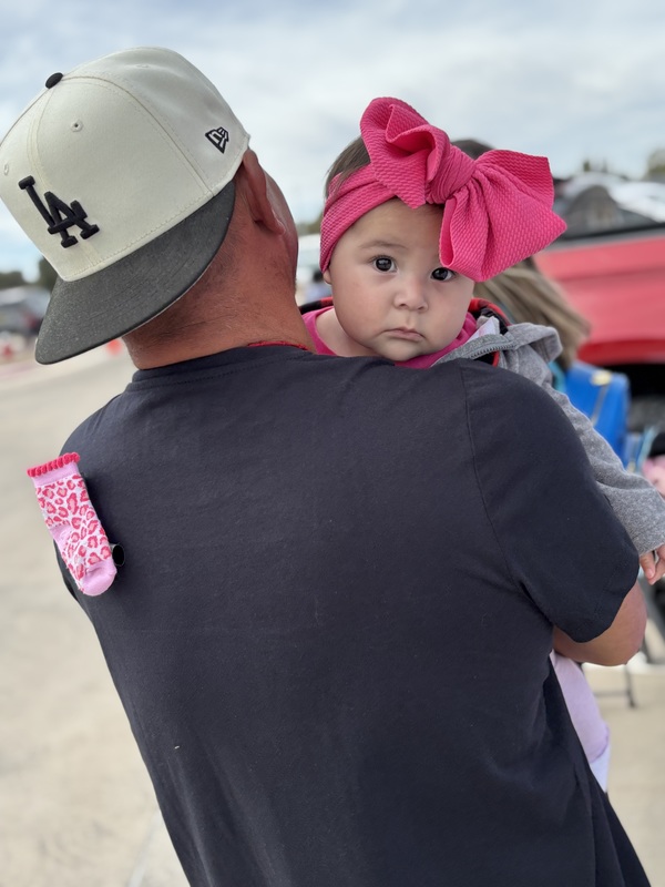 Man holding a baby dressed as "Boo" there is a sock on the back of his shirt