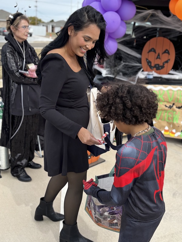Lady passing candy to student in costume