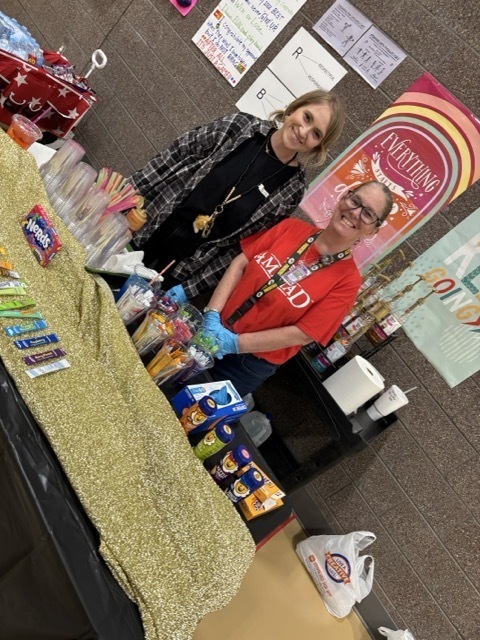 2 ladies standing in front of a table.