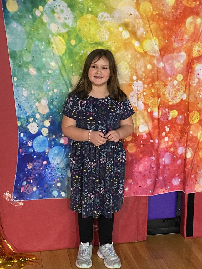 child poses under a rainbow mural