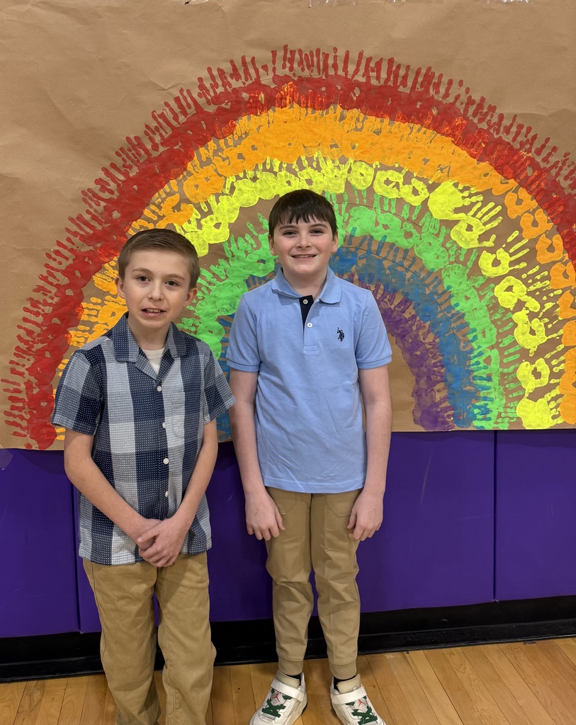 children pose under a rainbow mural