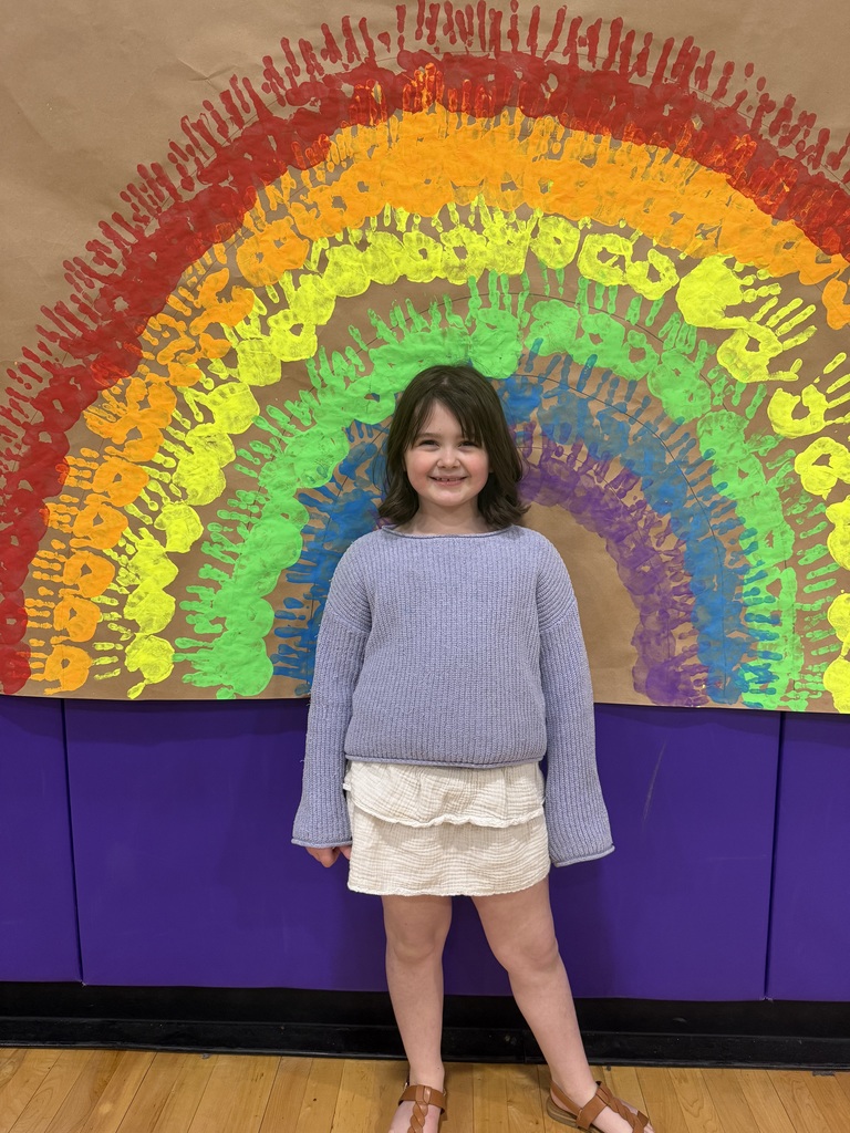 child poses under a rainbow mural