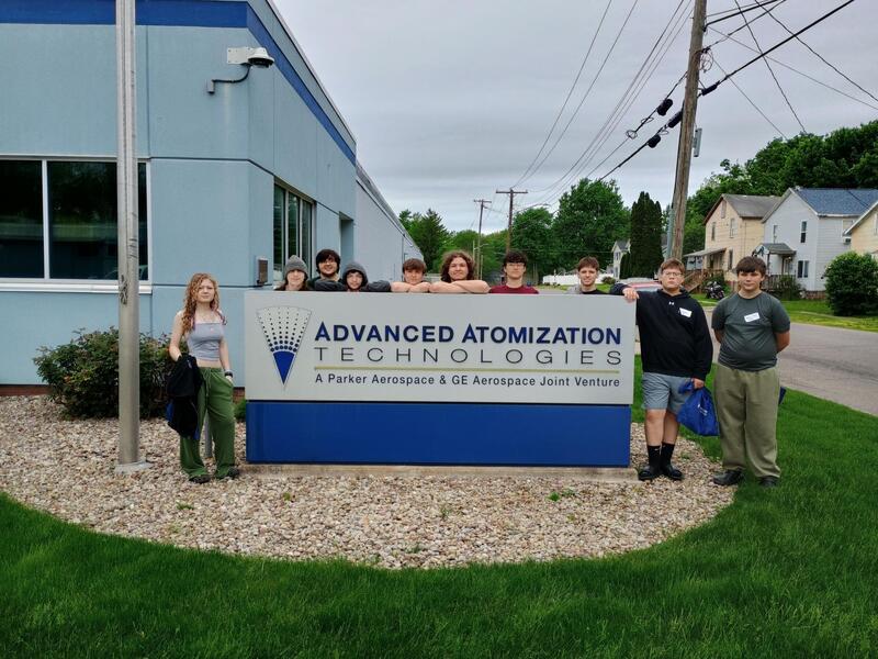 students standing by sign for aa technologies