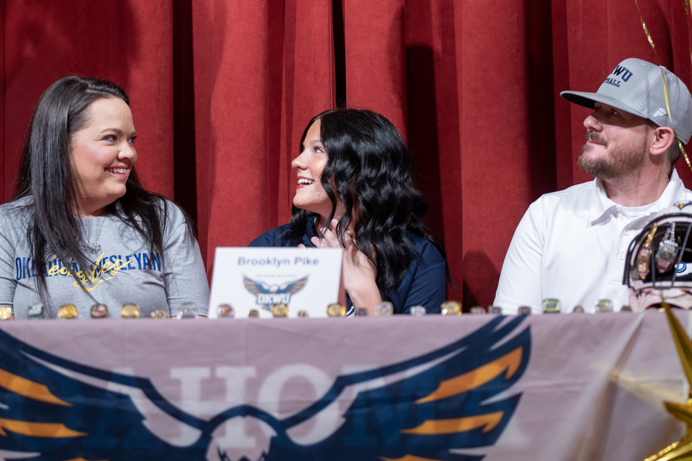 Student smiling at parents after she signs to play softball at college