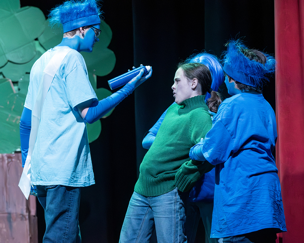 Junior High students acting out a scene. All but one student is in blue paint