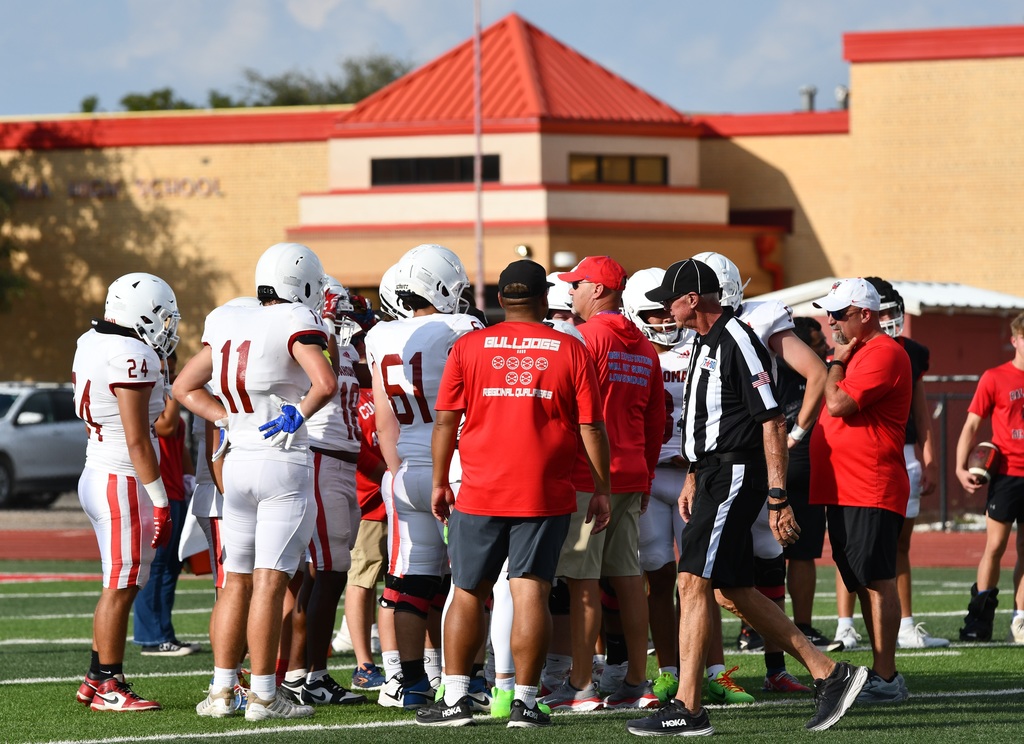 football players in a huddle with coaches