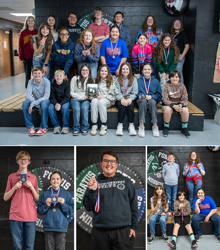 Students from a junior high one-act play ensemble post with their medals