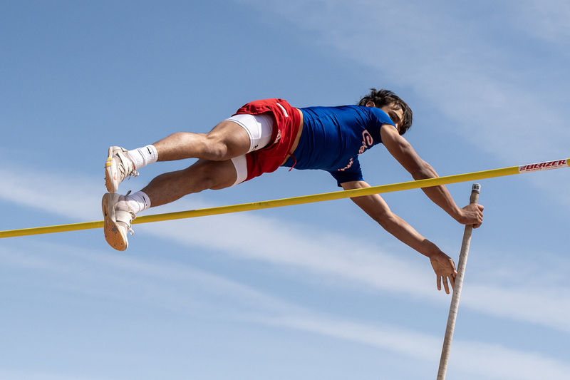 High school pole vaulter clearing the vaulting over the bar at a meet