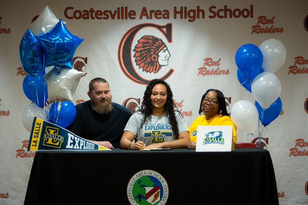 Picture of Kylee Bostic signing with her parents.