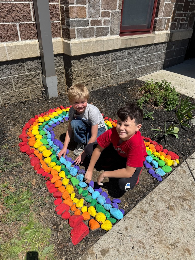 Rainbow students placing rocks in front of the school.