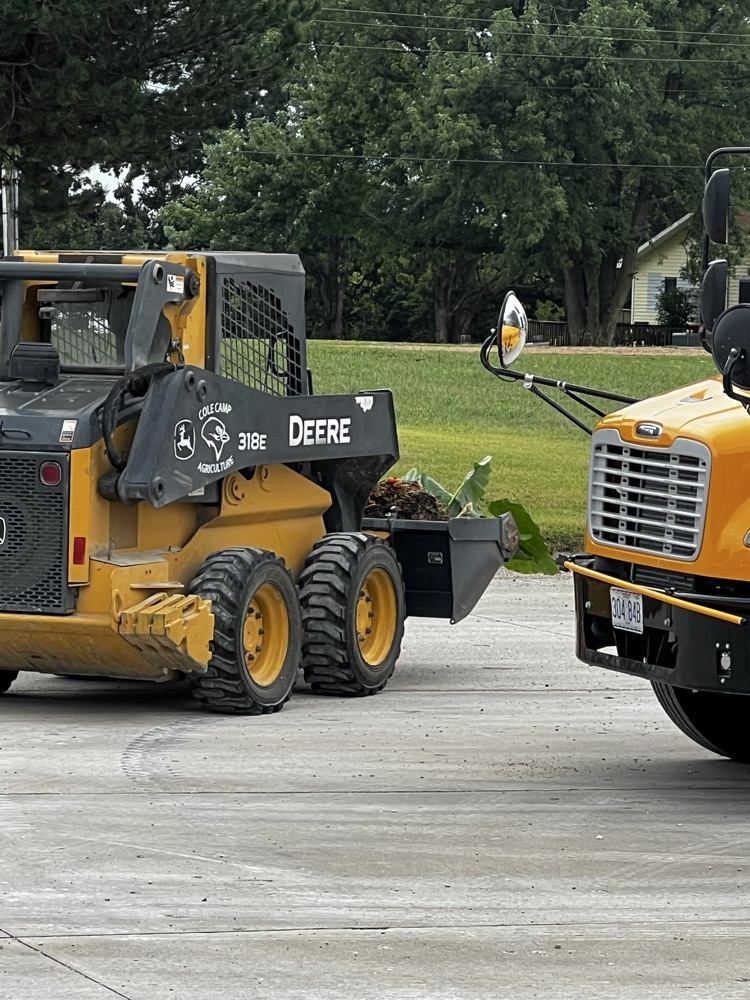 Garrett cleaning up vegetation around school and greenhouse