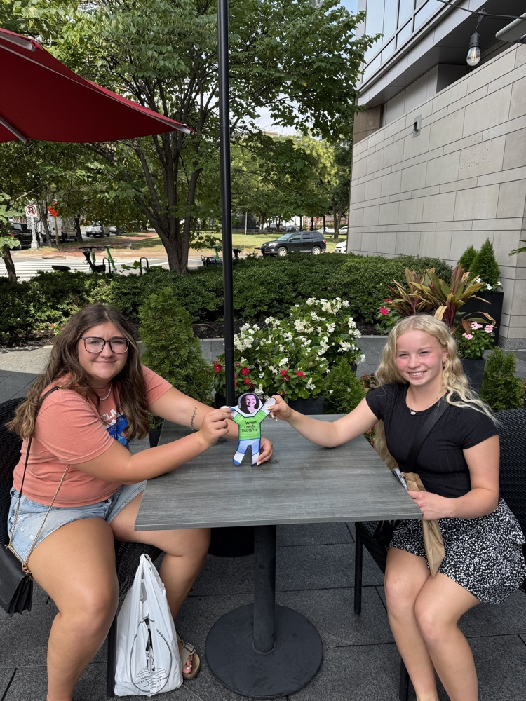 Students sitting at table posing with paper image