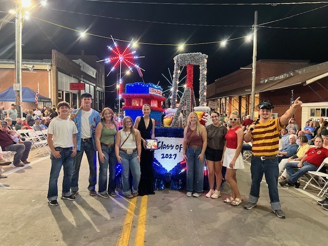 On the final night of the parade, some senior class members stand in front of the float with their People's Choice winning plaque.