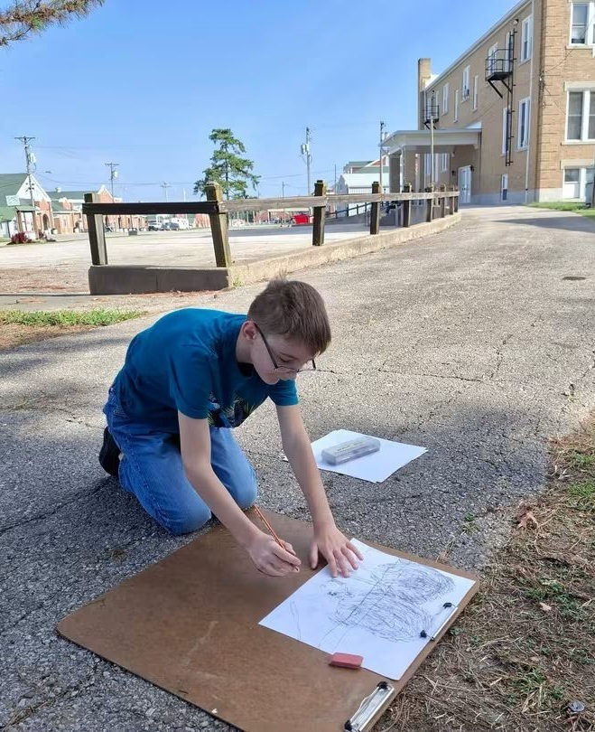 Student Cayden Noble sketching with charcoal pencil.