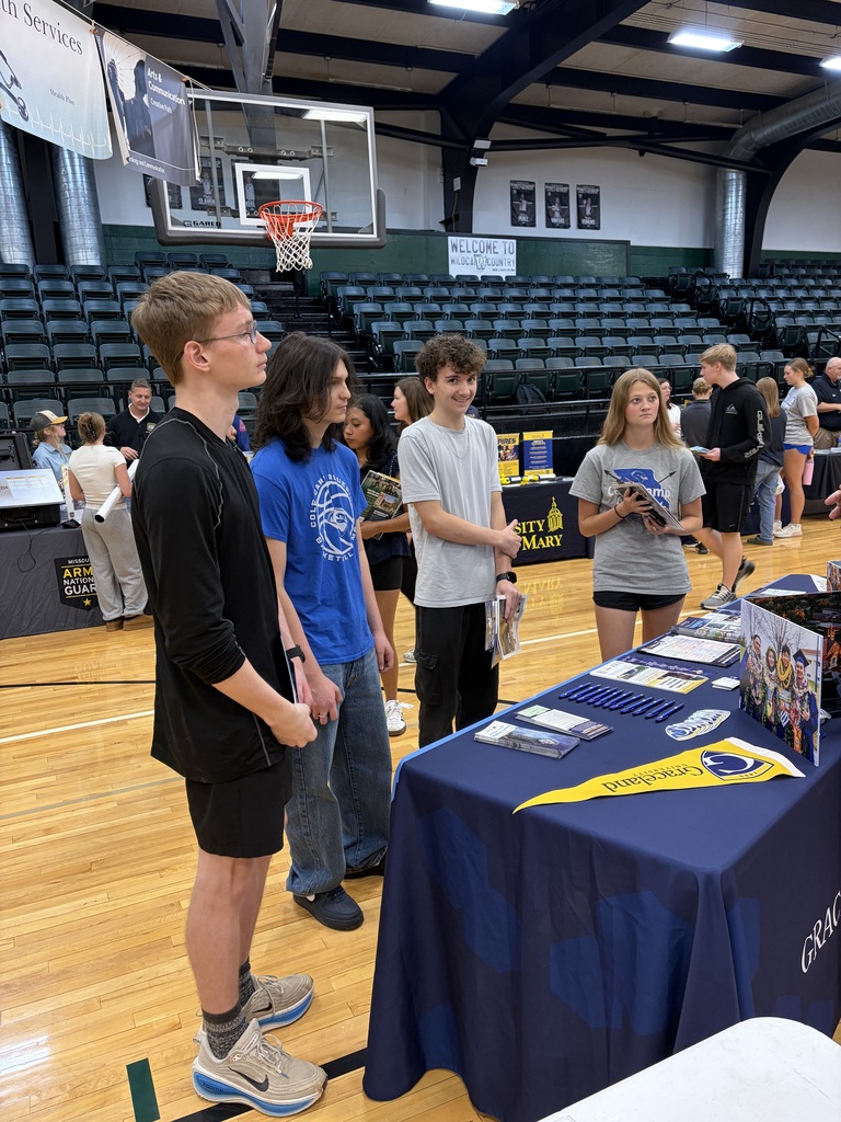 Several high school students standing around college fair display