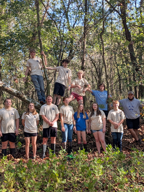 Several students from class standing in wooded area.