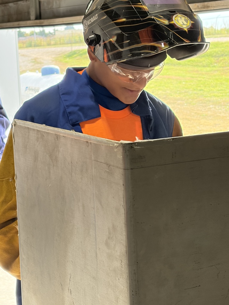 High School student in welding booth wearing a welding hood at Build My Future