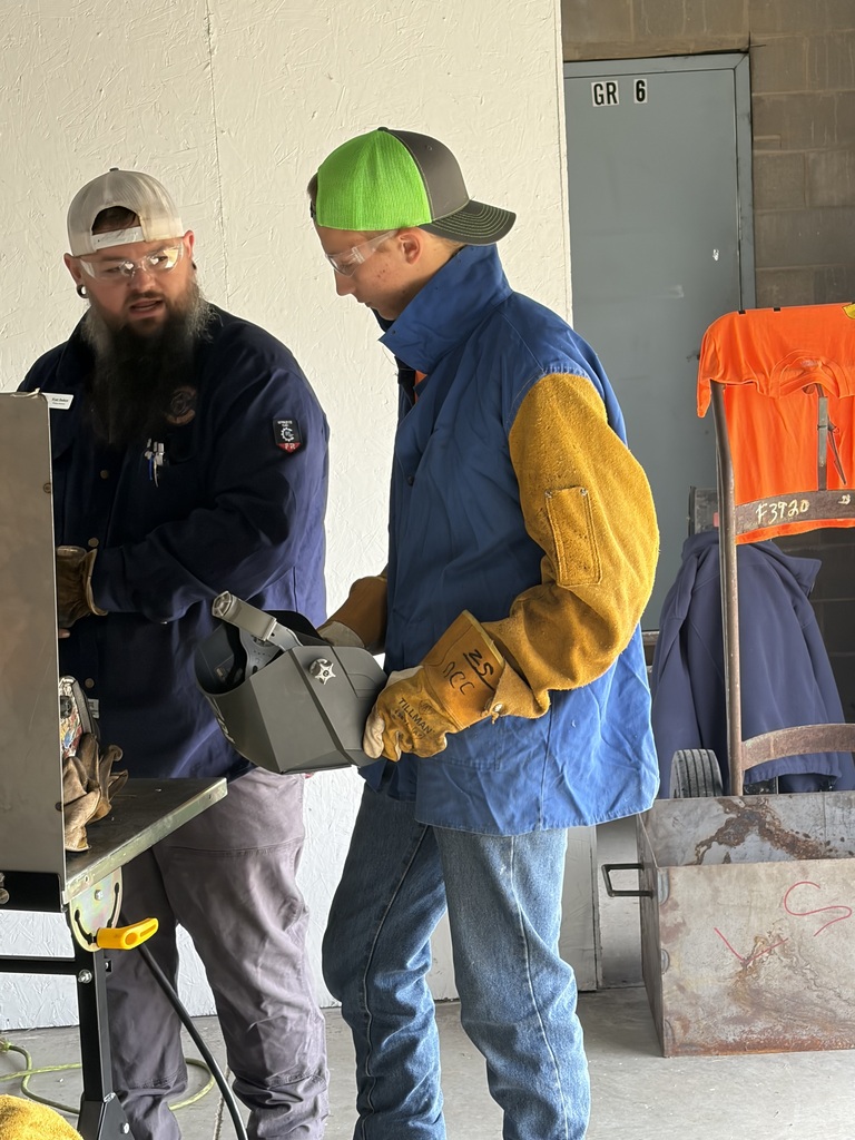 High school student putting on welding gear at Build My Future with instructor giving direction