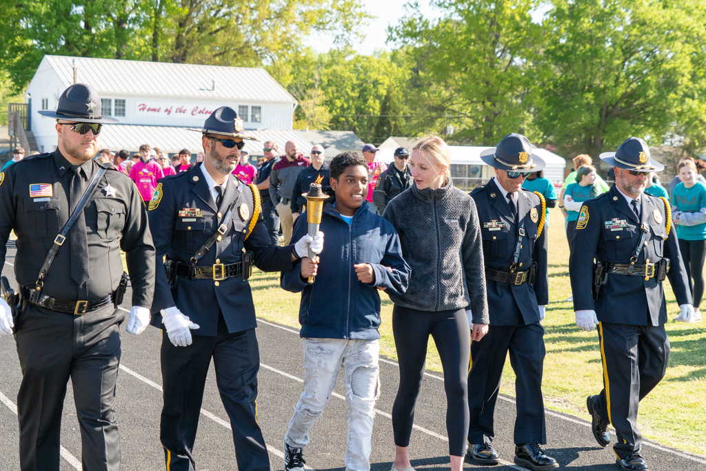 Student carrying torch with officers