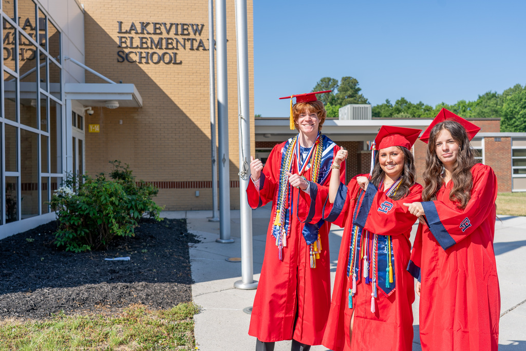 Senior Students outside of Lakeview and pointing at name of school