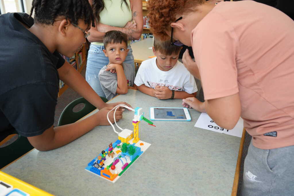 2 boys teaching little kids on iPad