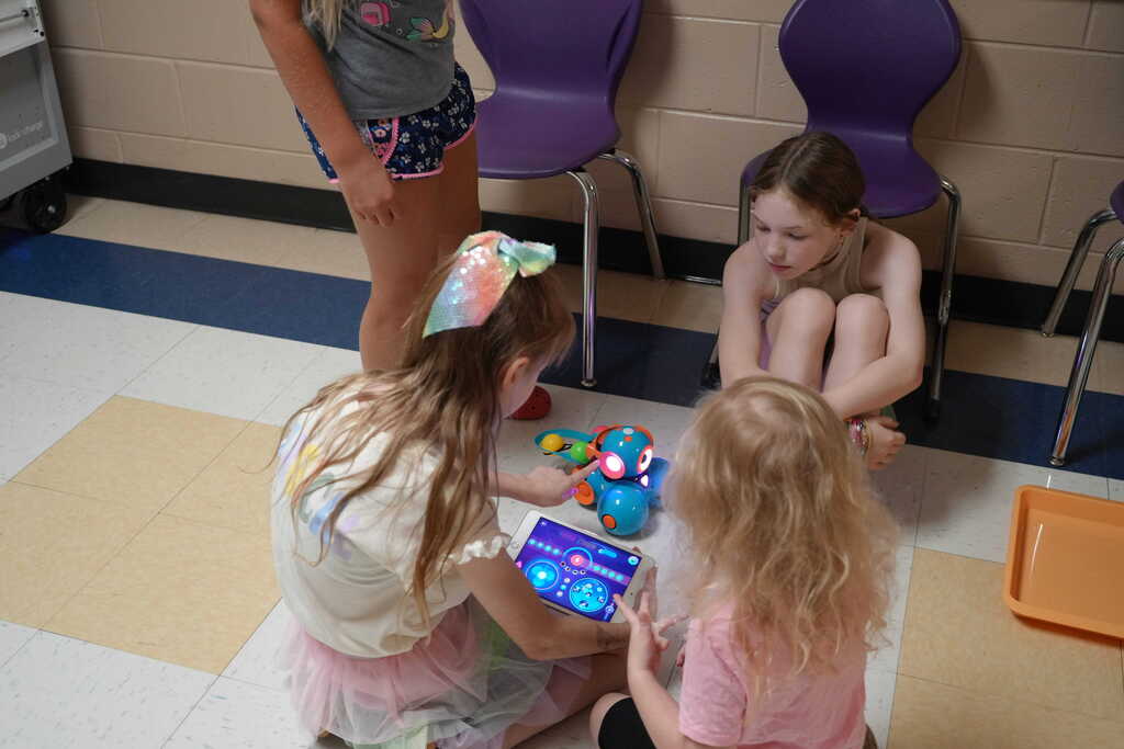 Girls Teaching Young Child Dash Robot with Ipad
