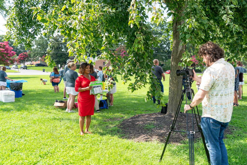 News reporter recording story with bag of free supplies for students