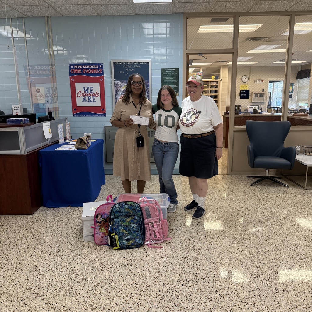 Two community supporters present a donation to Lakeview Elementary School, including a monetary gift and backpacks filled with school supplies.