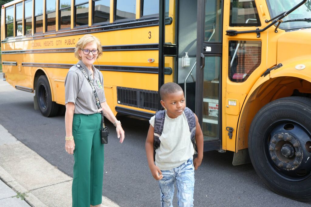 Principal with student getting off of bus