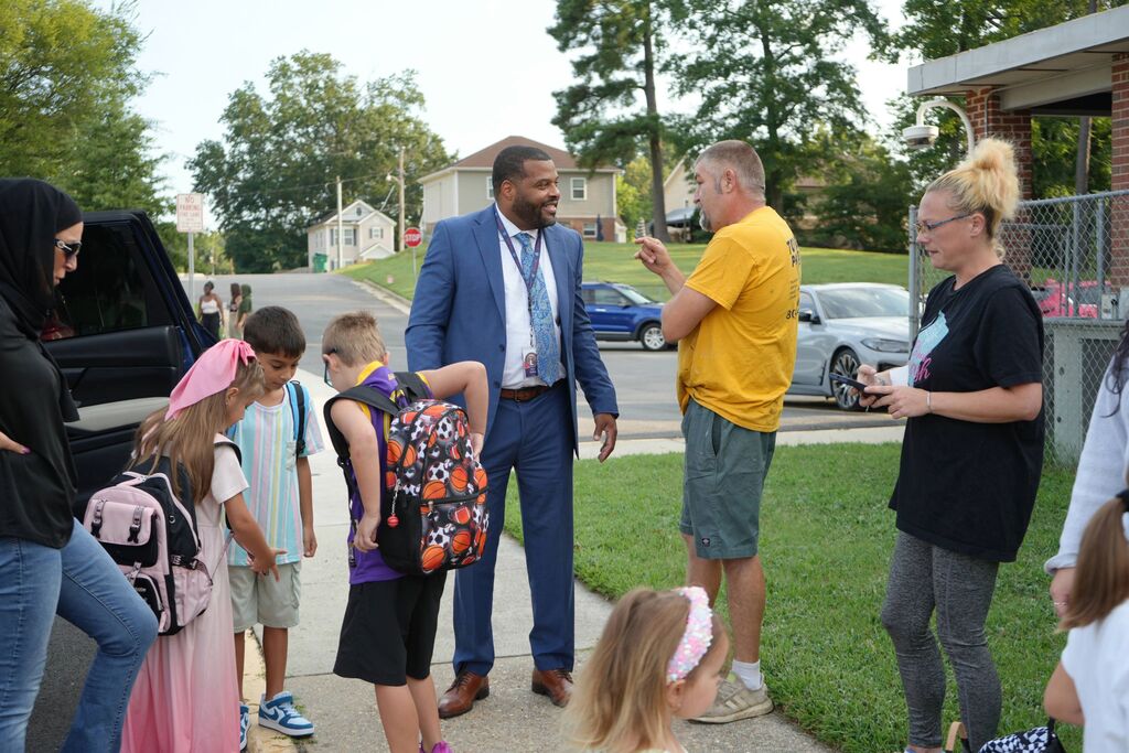 Superintendent talking with parent surrounded by children