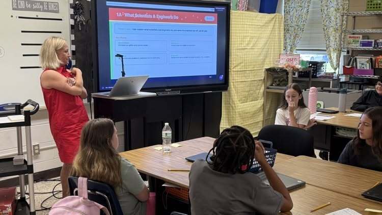 Teacher at board teaching student what scientists and engineers do