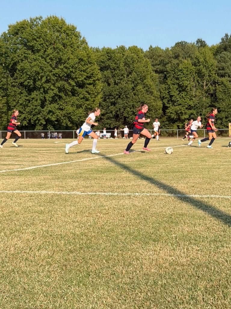 Middle School Girls Soccer player running on field with ball