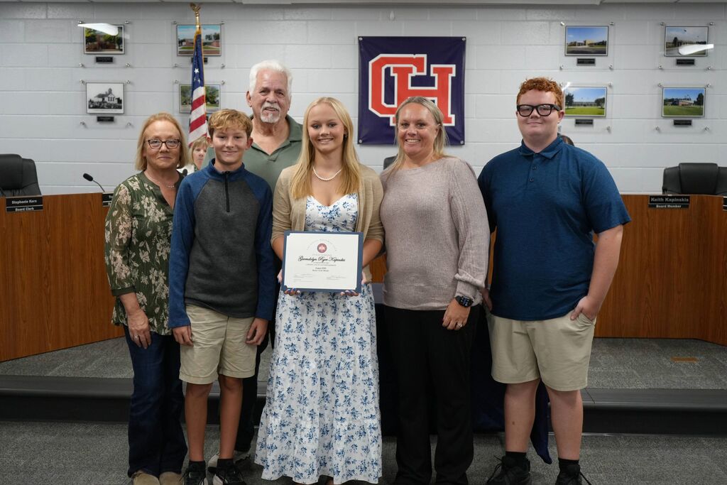 August senior of the month in a group picture with her family, holding her certificate of recognition