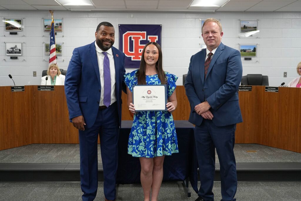 Superintendent, September Senior of the Month, and Board Chair in a group photo. Student is holding certificate of achievement.