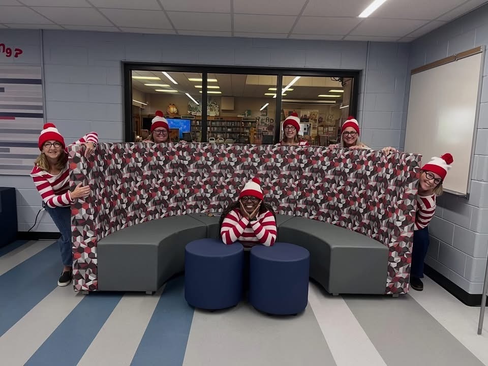 Guidance Team hiding behind sofa dressed in matching Where's Waldo Clothes