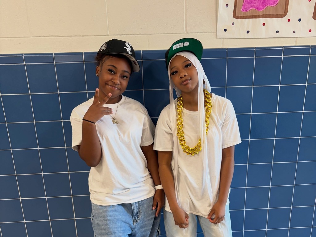 Girls dressed up in matching white tshirts, jeans, and hats for twin day