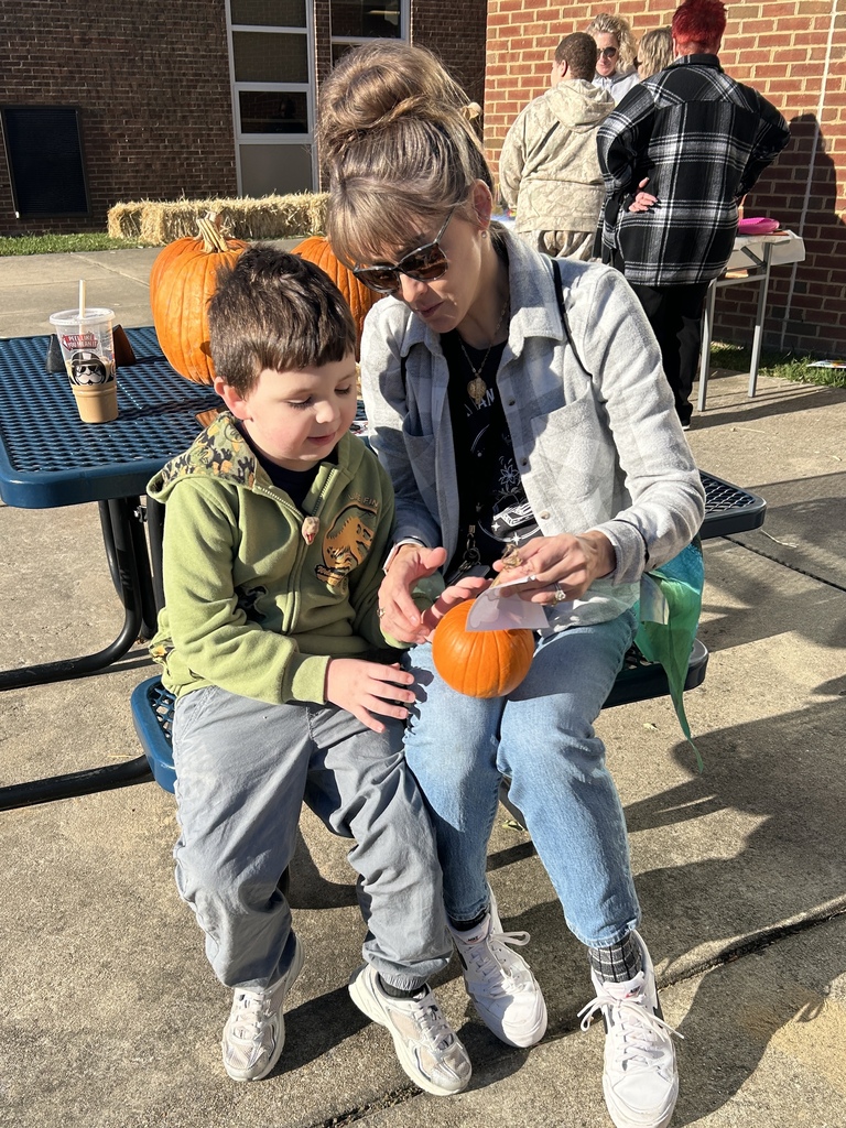 Boy with Teacher putting stickers on pumpkin