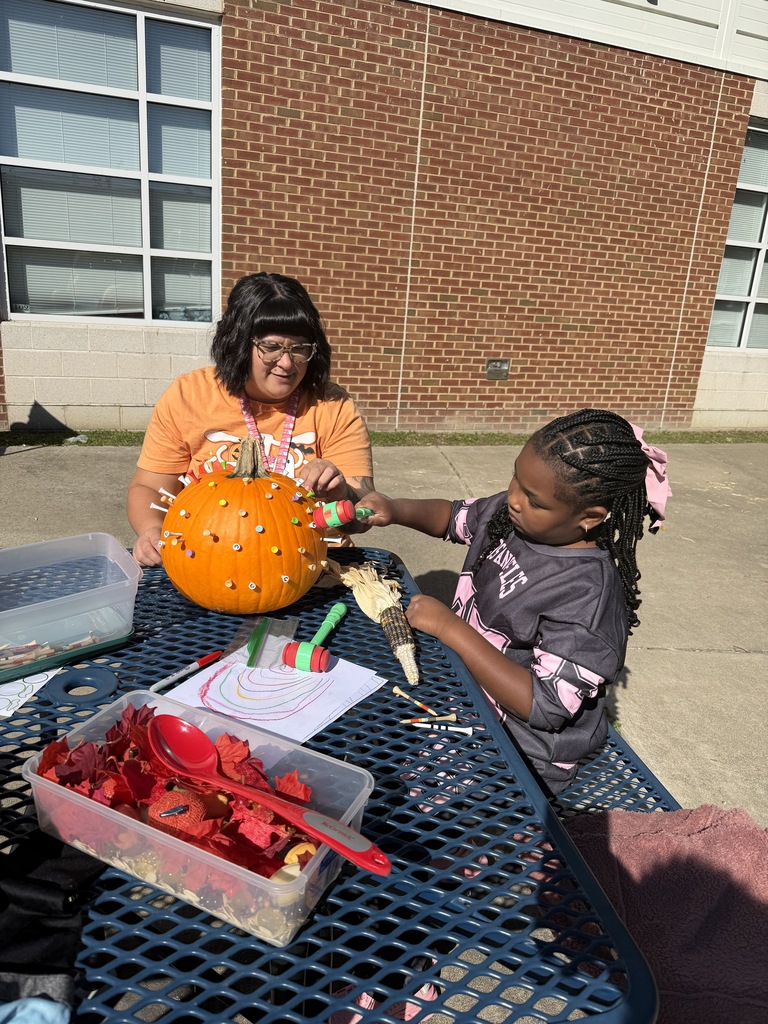 girl with teacher hammering golf tees into pumpkin