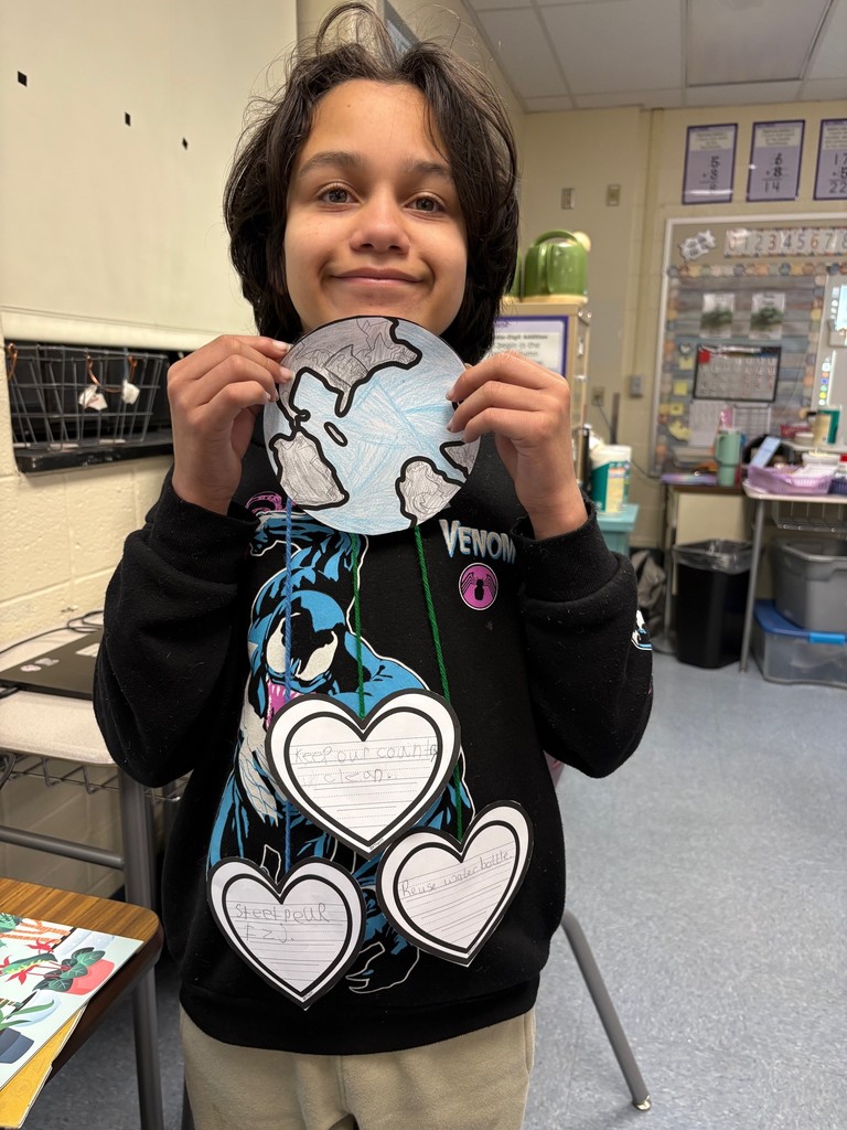 student holding an earth day project shaped like the earth